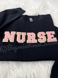 Model wearing chenille NURSE patch crewneck sweatshirt in grey - nurse birthday gift