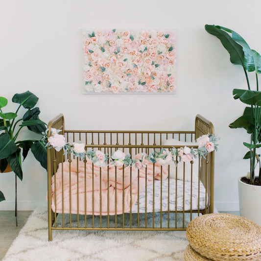 Pink floral wall hanging displayed above wooden crib in nursery