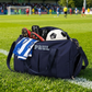 Navy blue sports bag with 'PAUL' branding on a soccer field.
