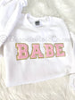BABE patch sweatshirt flat lay in white with light pink chenille letters