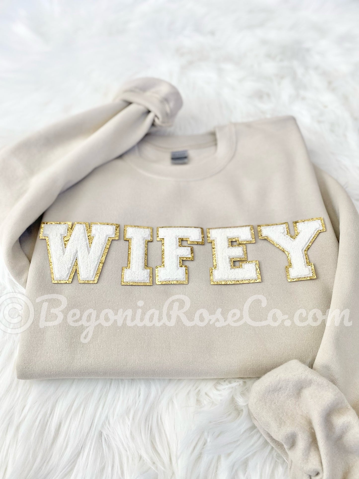 Tan sweatshirt with a gold trimmed wifey patch on white fur