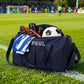 Navy blue sports bag with 'PAUL' branding on a soccer field.