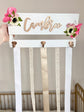 Bow holder with painted metal hooks and floral arrangement