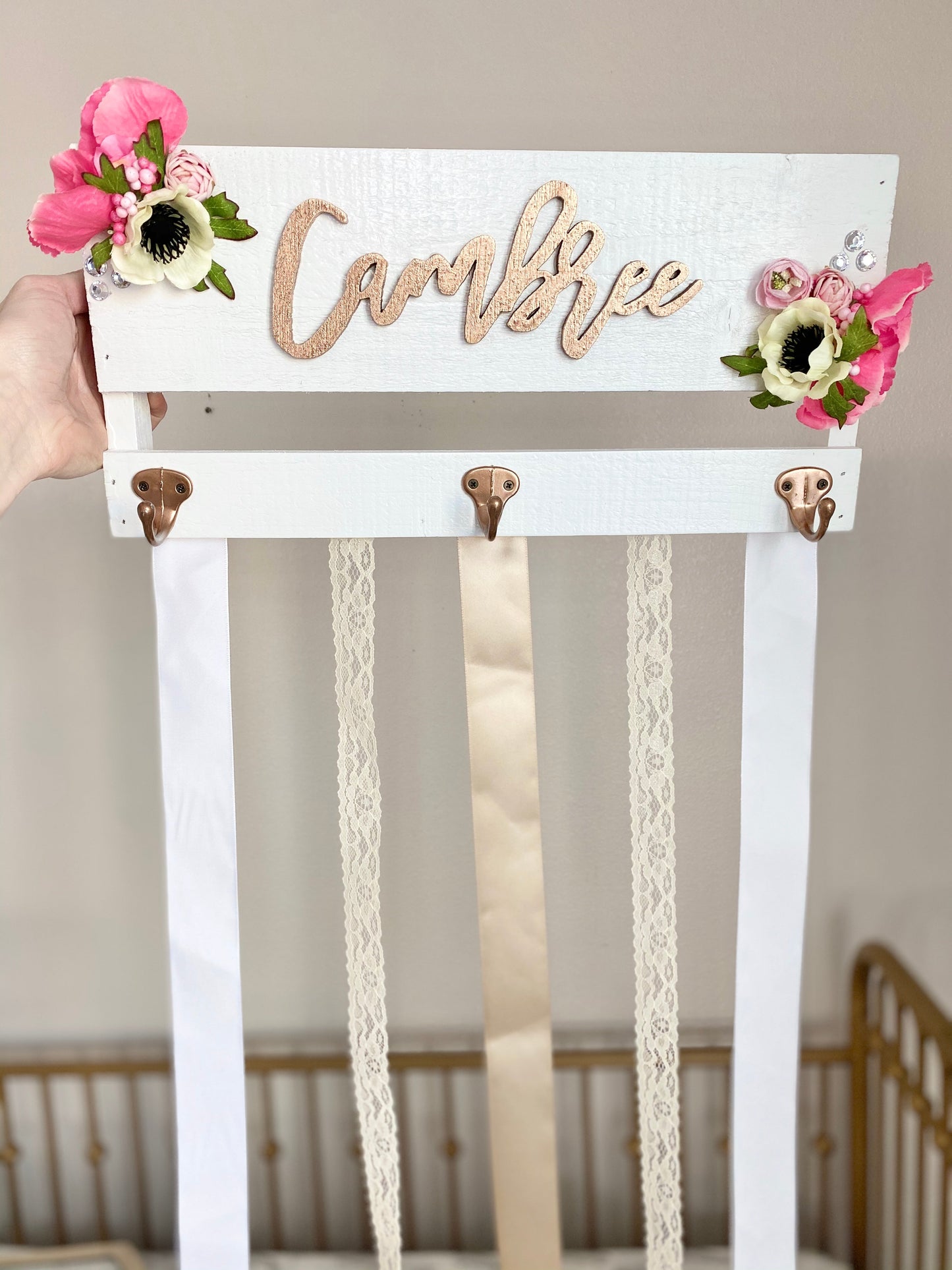 Bow holder with painted metal hooks and floral arrangement