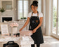 Woman wearing black multi-pocket apron in a professional salon with beauty products