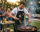 Man in a grill house apron grilling meat at an outdoor party