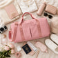 Pink duffel bag with a custom name surrounded by travel essentials