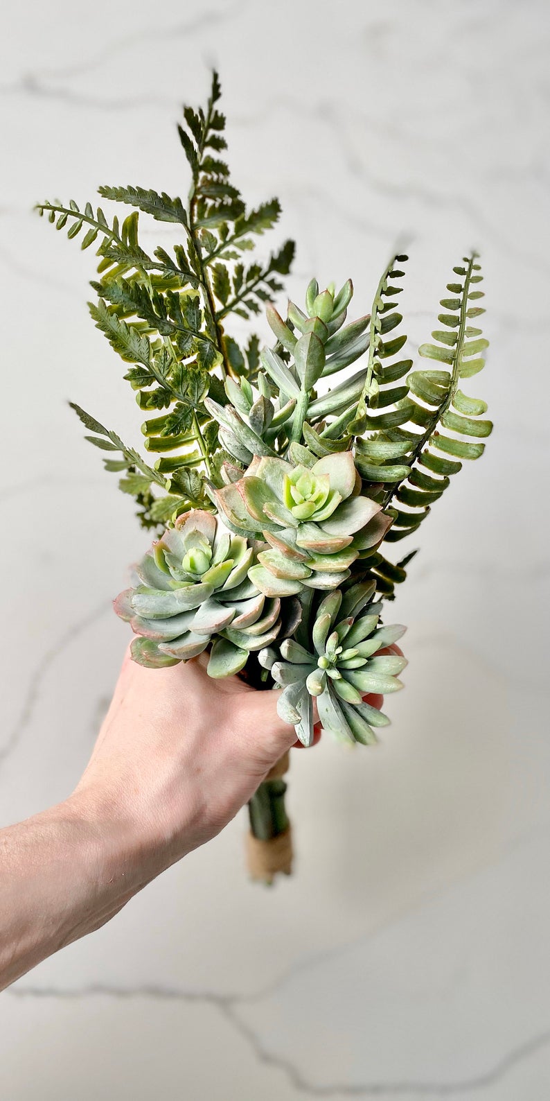 Faux succulent bouquet close-up showing four succulent varieties with greenery