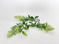 Close-up of faux tropical greenery sprig showing green and dusty purple coloring